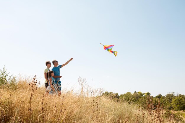 Счастливый отец с детьми запускает воздушного змея на природе