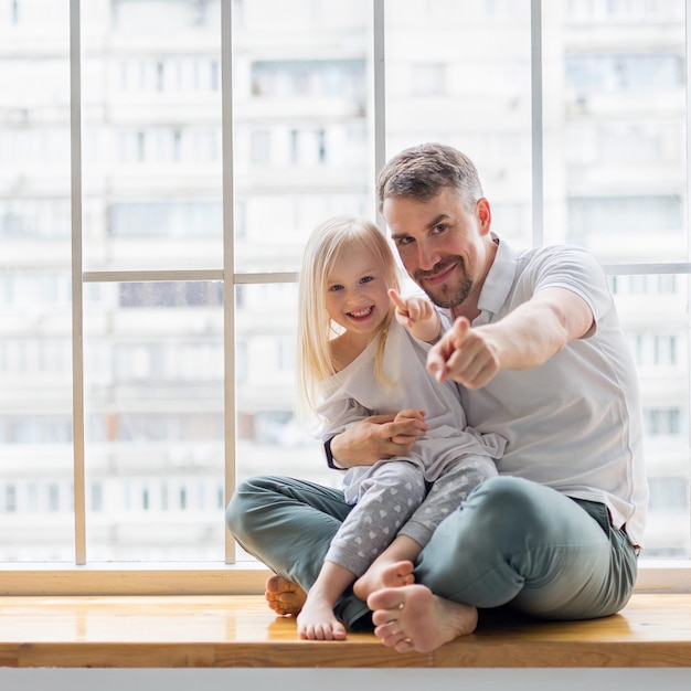 Happy father with daughter pointing with fingers against of window