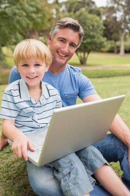 Happy father with his son using laptop in the park