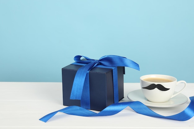 하 나무 테이블 클로즈업에 수염과 선물 상자를 가진 Happy Father's Day 컵