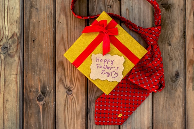 Happy Fathers Day ambachtelijke geschenkdoos met rode stropdas op een rustieke houten achtergrond. Wenskaart
