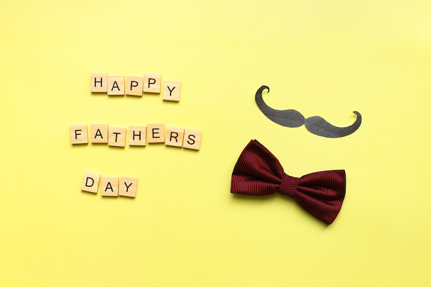 Happy fathers day Flat lay mustache bow tie on a yellow background Fathers day lettering word