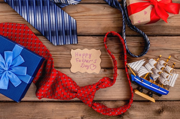 Happy Fathers Day gift boxes with red and blue ties on a rustic wood background. Top view card.