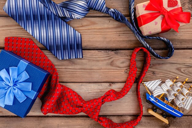 Happy Fathers Day gift boxes with red and blue ties on a rustic wood background. Top view card.