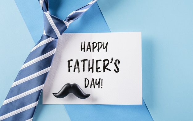 Happy Fathers Day inscription in celebrated card and plaid tie on pastel blue background