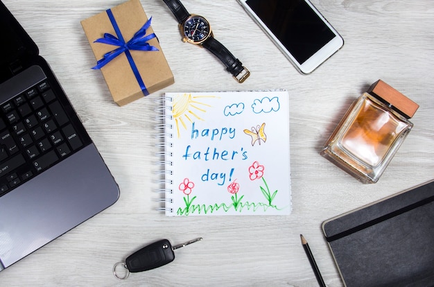 Iscrizione felice della festa del papà con il taccuino del computer portatile e la tazza di caffè su fondo di legno