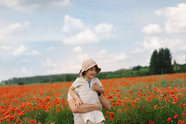 Happy fathers day little boy and father are playing in a beautiful field of red poppies