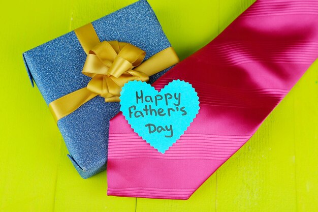 Happy fathers day tag with gift boxes and tie on wooden background