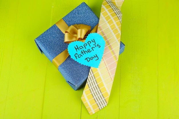 Happy fathers day tag with gift boxes and tie on wooden background