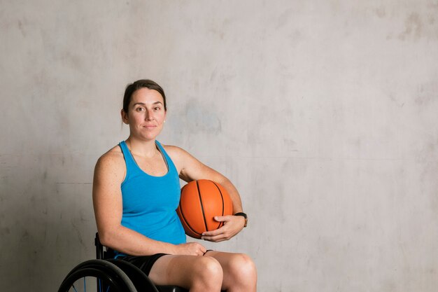 Happy female athlete in a wheelchair with a basketball