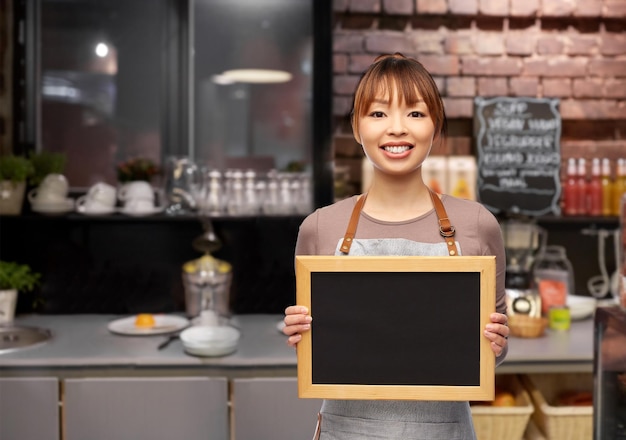 happy female barista with chalkboard at restaurant