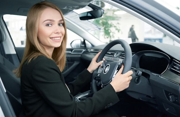 Happy female client sitting in new comfortable automobile