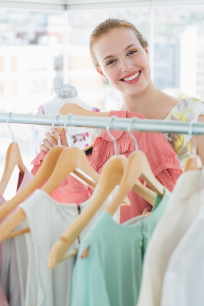 Happy female customer selecting clothes in store