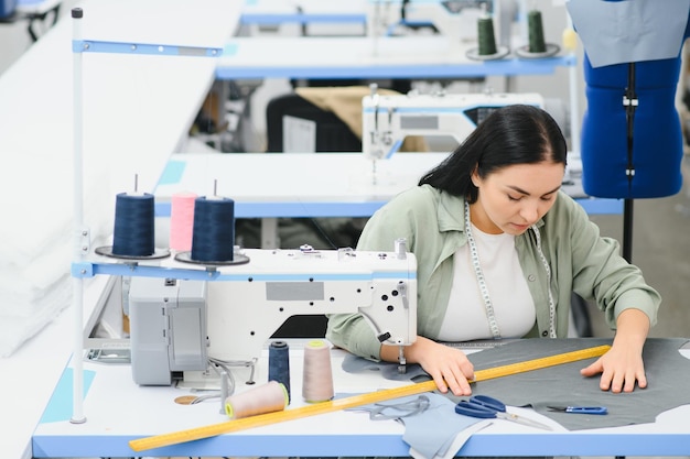 섬유 공장에서 재봉틀로 일하는 행복한 여성 양장점