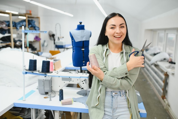 Happy female dressmaker working with sewing machine at textile factory