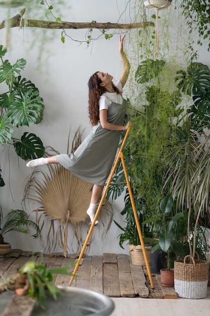 Happy female florist on stepladder with tenderness preparing houseplants for sale indoor gardening