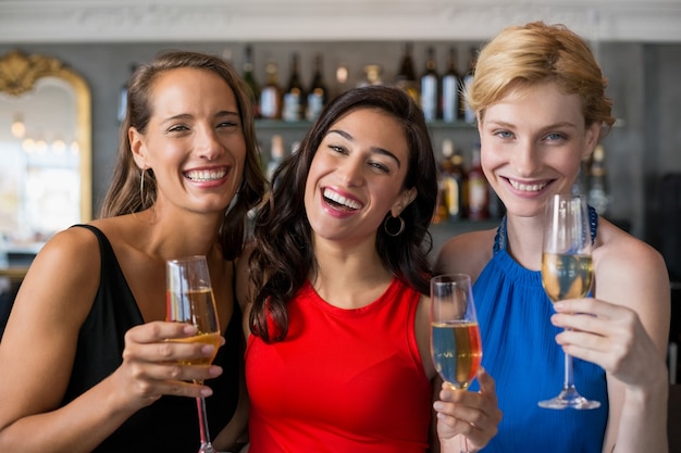 Amici femminili felici che tengono vetro della scanalatura di champagne