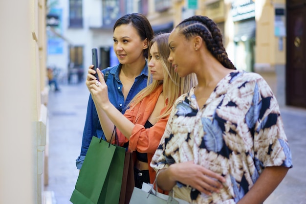 Photo happy female friends taking picture on street