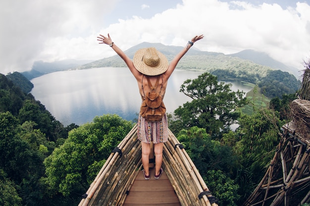 Happy female hiker standing on a cliff with her arms up in the air feeling free. Active healty concept