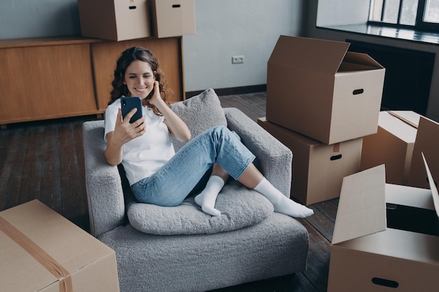 Happy female homeowner tenant chatting by video call discussing
relocation to new home on moving day