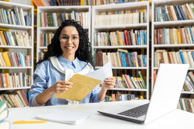 Photo a happy female librarian with curly hair wearing glasses manages paperwork and digital entries on