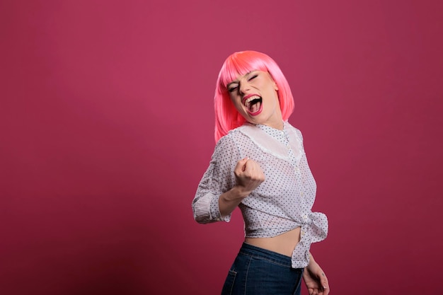 Happy female model celebrating successful triumph and victory,\
enjoying lucky win and achievement celebration in studio. confident\
woman with pink hair feeling excited about winning\
satisfaction.