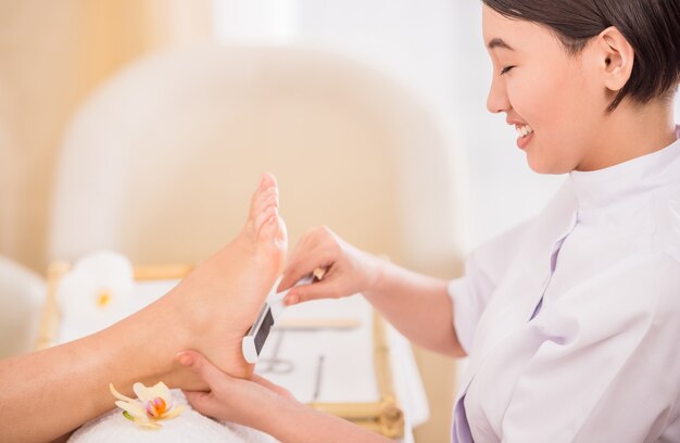 Photo happy female pedicurist working on a client at spa.