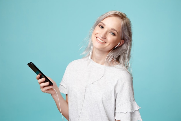 Happy female person with earphones and phone listening to the music in the studio.