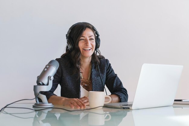 Happy female radio host broadcasting live in a studio