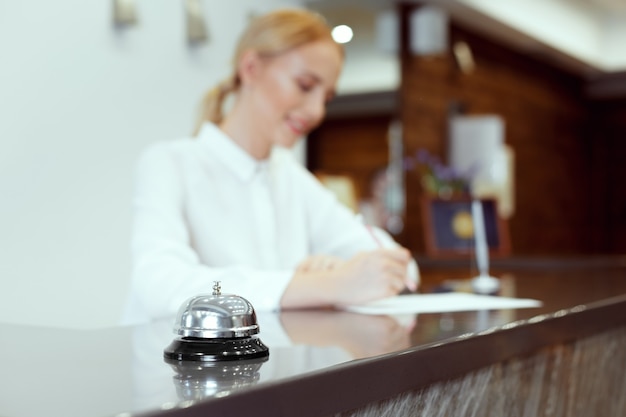 Photo happy female receptionist standing at hotel counter