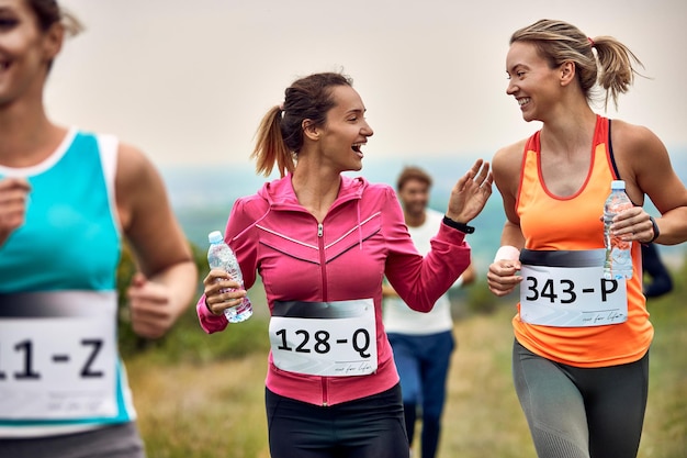 happy female runners communicating while participating in marathon in nature