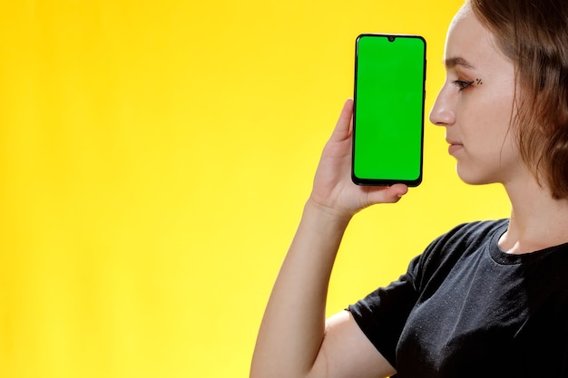 緑の画面、ソーシャルネットワークアプリでスマートフォンを示す幸せな女性。