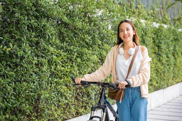 사진 행복한 여성이 시내 도로에서 자전거를 타고 길을 고 웃으며 eco 환경 라이프 스타일 아시아 젊은 여성이 시골의 여름에 자전거와 함께 산책합니다.