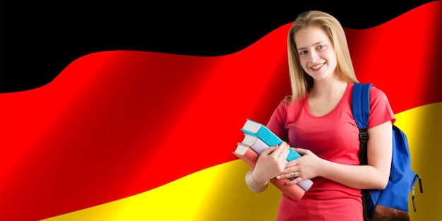 Happy female student holdimg books on german flag