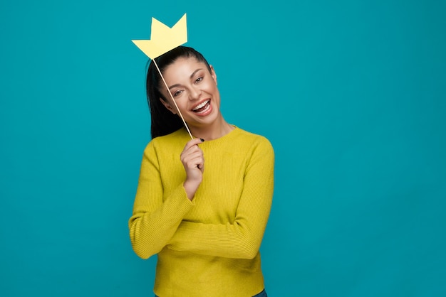 Studentessa felice che posa con la corona in studio