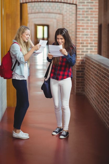 Happy female students looking at results in the university 