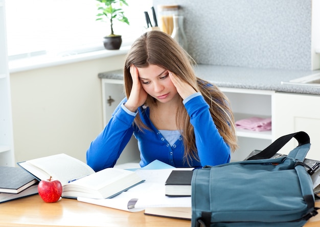 Happy female teenager studying in the kitchen