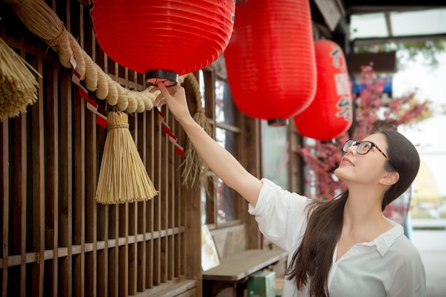 幸せな女性観光客は、美しい伝統的な提灯を見て眼鏡をかけた祭りを祝う日本茶に参加し、日本旅行で東洋文化を楽しみ、お祝いを意味する日本語のテキスト