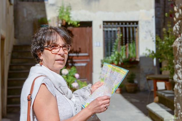 Happy female tourist searching road on map in city during vacation