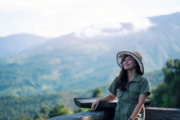 A happy female traveler with a beautiful green mountains landscape on foggy day