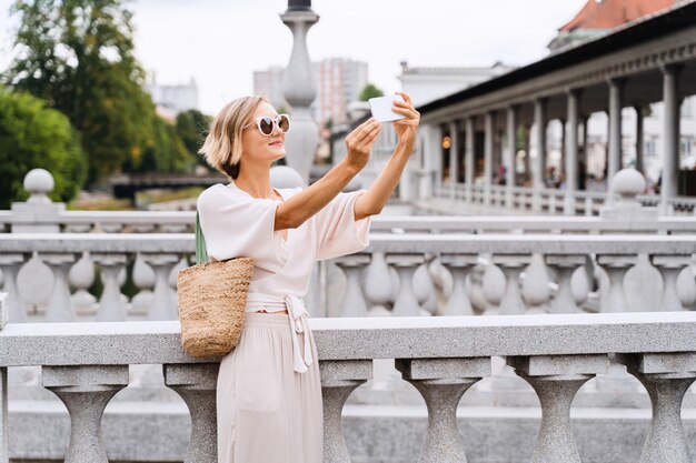 Happy female using smart phone on the Triple bridge in Ljubljana Slovenia Europe