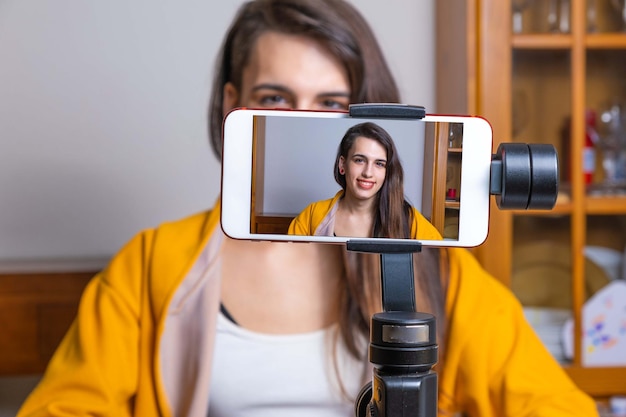 Photo happy female vlogger live streaming from living room using smartphone