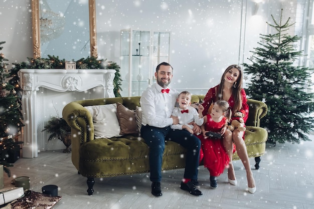 Happy festive family smiling posing at luxury december holiday interior at christmas tree background