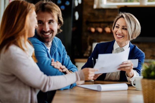 Happy financial advisor and her clients going through paperwork during a meeting