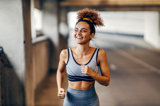 A happy fit runner is running under the underpass with a smile on her face with minimum effort