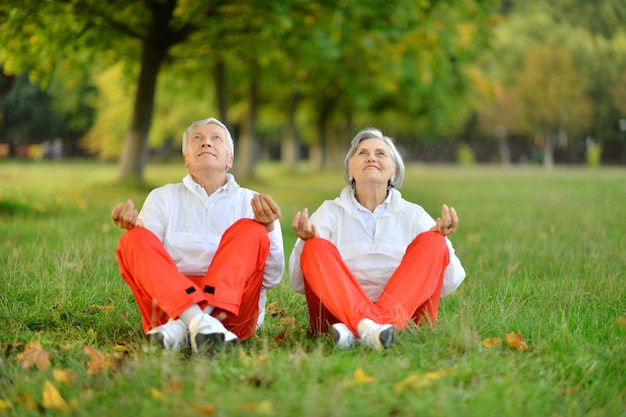 Photo happy fit senior couple exercising in autumn park