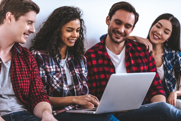 The happy four people with a laptop sitting on the floor