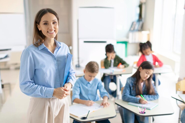 Photo happy friendly female teacher smiling at camera during lesson at elementary school while pupils
