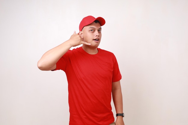 happy friendly handsome young asian courier standing while making phone hand gesture against white background
