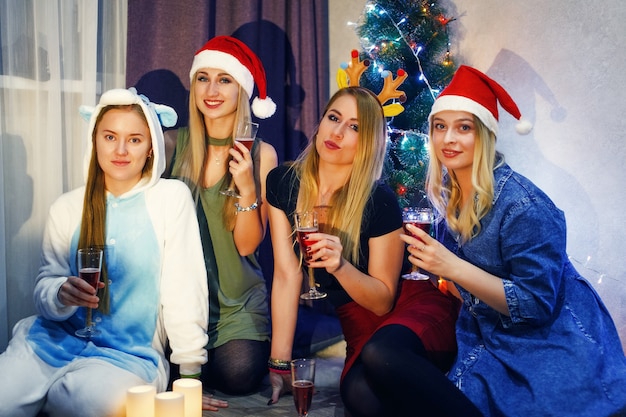 샴페인 한 잔과 건배를 하며 크리스마스나 새해를 축하하는 행복한 친구들. 집에서 크리스마스를 축하하는 5명의 아름다운 소녀들